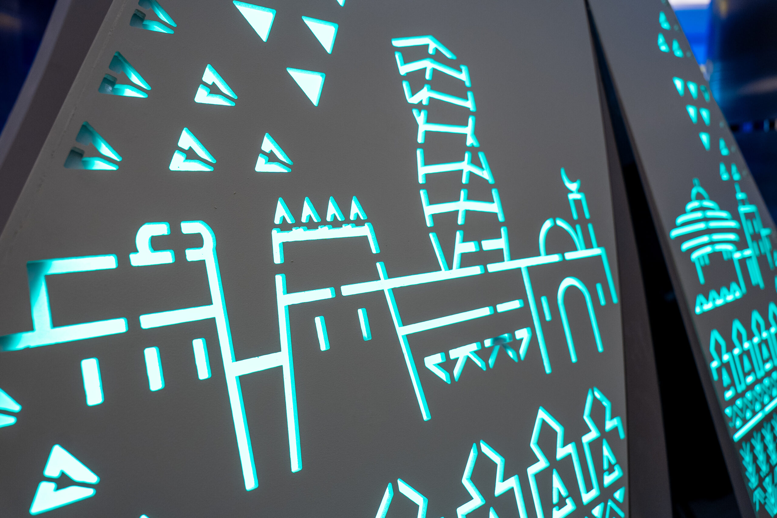 Riyadh skyline motif cut into a tower panel, lit blue