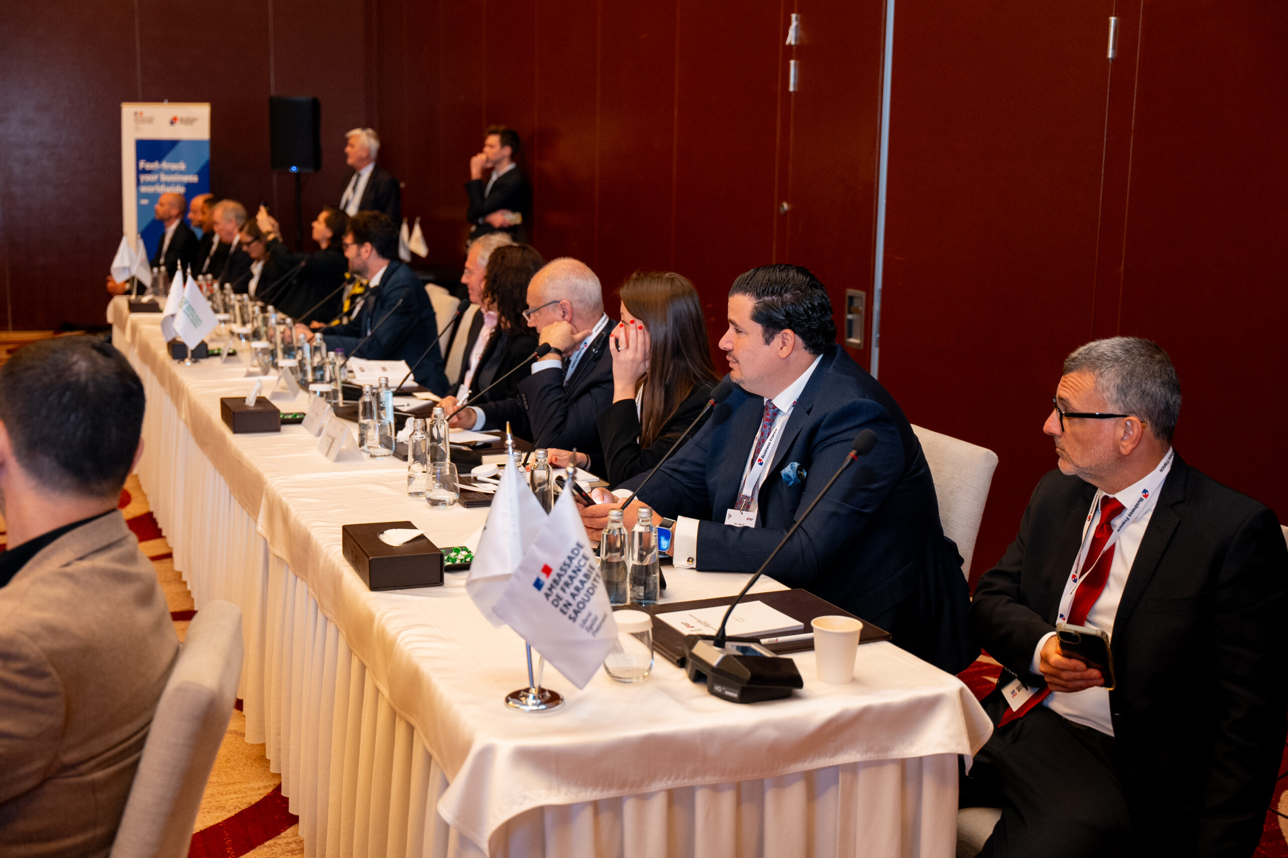 A roundtable ringed with French and Saudi flags