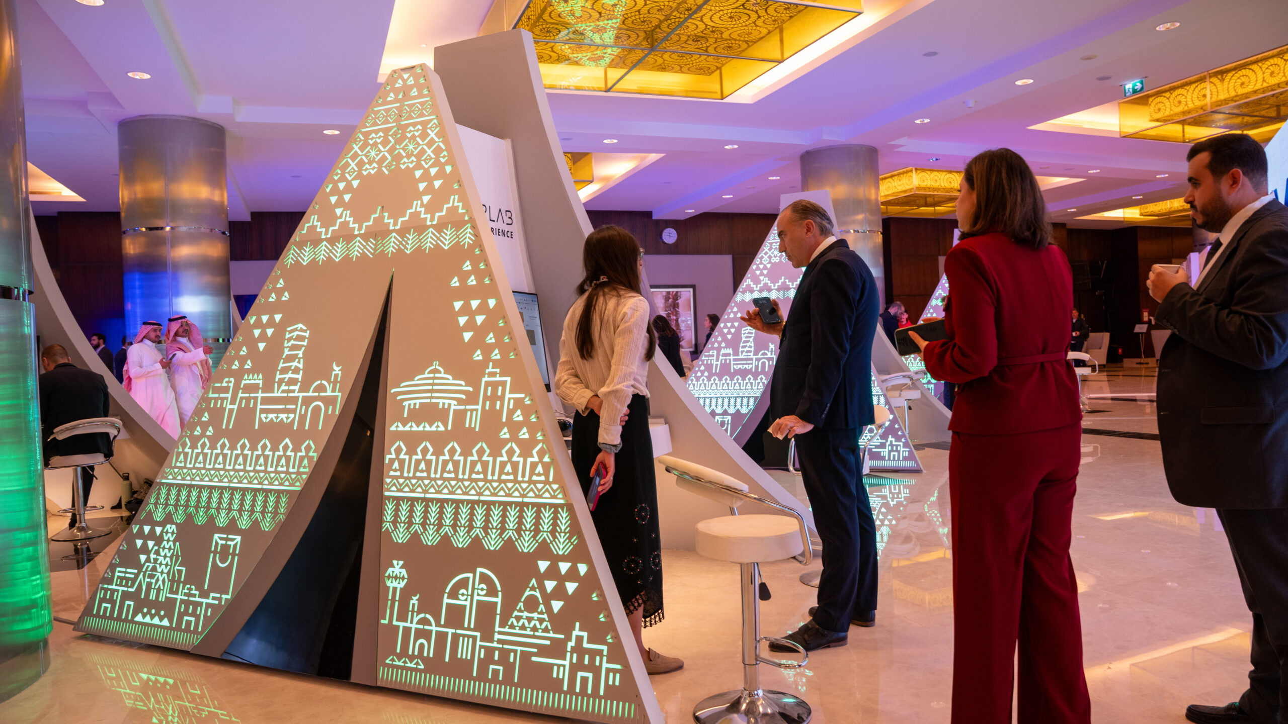 The Saudi face of the towers, lit green, with guests in the foyer